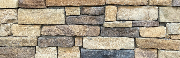 rock stone wall building facade structure with black brown and tan cut rock bricks