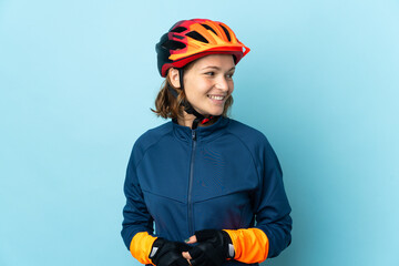 Young cyclist woman isolated on blue background looking side