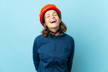 Young cyclist woman isolated on blue background laughing