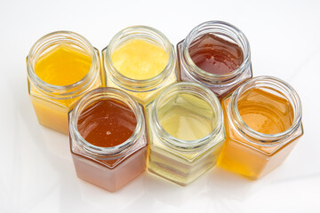 Hexagonal jars with different types and colors of fresh flower honey. vitamin food for health and...