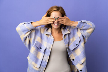 Young Georgian woman isolated on purple background covering eyes by hands and smiling