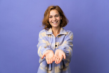 Young Georgian woman isolated on purple background holding copyspace imaginary on the palm to...
