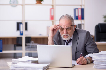 Naklejka premium Old male employee unhappy with excessive work in the office