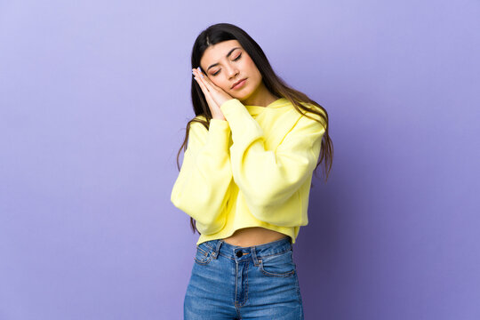 Young brunette woman over isolated purple background making sleep gesture in dorable expression