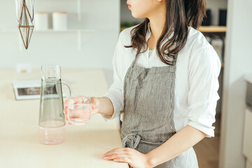 女性がキッチンで水の入ったグラスを持っている　woman water hand