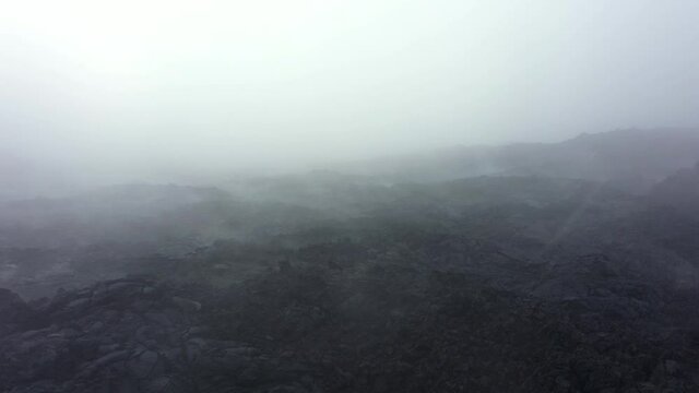 Drone video above the frozen lava of a volcano. Ash and snow