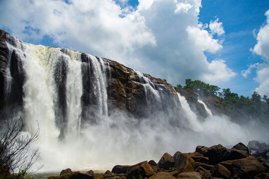 Water falling from the sky during blue and white cloudy sky, The most beautiful Athirapally waterfalls, Kerala, India