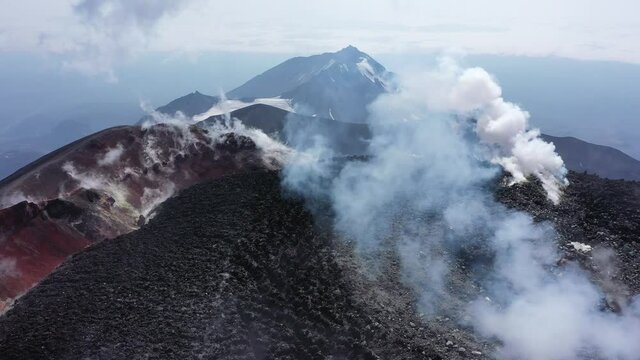 Avachinsky drone volcano summit video. Kamchatka, active volcano, red soil, steam, solidified black lava, sulfur