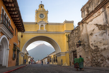 People walking through the Santa Catalina Arch early in the morning going to the center of the city. Agua Volcano can be seen in the background