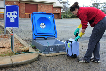 Australian woman emptying a caravan tank toilet cassette in a dumping point