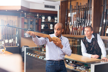 Two men choosing pneumatic weapon in military store