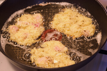Frying potato pancakes with a piece of fish fillet.