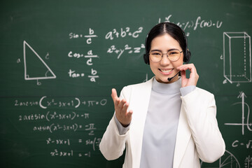 Young asian teacher woman wearing headset speaking video conference with student. Female teacher training the mathematics in classroom blackboard online course.