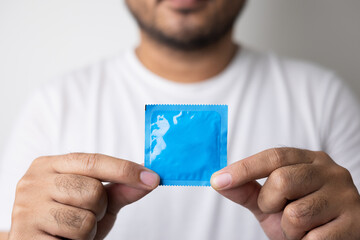 The young man showing the condom into camera. Campaign for safe sex and contraception. Close up...
