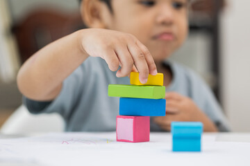 Close up Children hand Practice the skills of playing with wooden toys on the table in living room. Asian little boy education from home. Developing children's learning before entering kindergarten