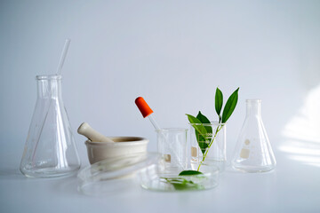laboratory glassware and cosmetic glass bottle on grey background.