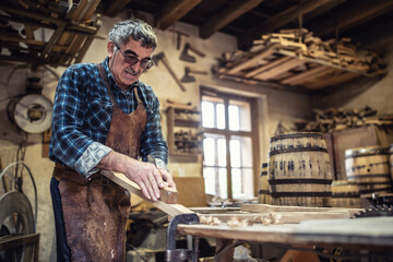 Building wooden barrels for storing aged alcohol by an older man in a vintage workshop