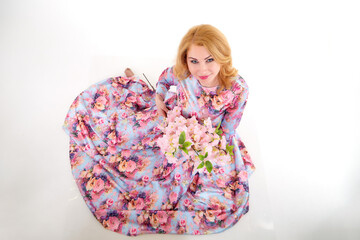 Happy beautiful woman with long blond curly hair posing with flowers in studio on white background