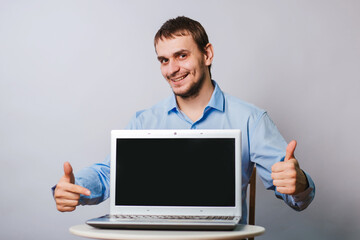 A man in a blue shirt on a white background with a laptop. The guy office worker shows on a blank computer screen. Sample