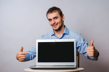 A man in a blue shirt on a white background with a laptop. The guy office worker shows on a blank computer screen. Sample