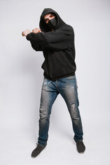 A masked bandit in a black hoodie, jeans and a bat on a white background.