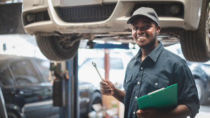 African maintenance male checking car with use wrench , service via insurance system at Auomobile...