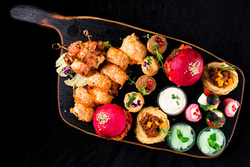 set of food on a wooden tray, a burger and snacks on a dark background