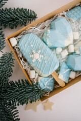 Fototapeta na wymiar An open cardboard box with Christmas cakes. Different confectionery cakes of blue color. Chocolate, spruce branches, decoration in the form of snowflakes.