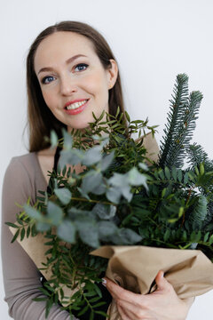 portrait of a Caucasian young woman florist with a winter bouquet in her hands. a bouquet of greenery in tap paper. Christmas and New Year.