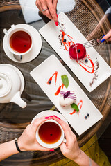 two female friends are eating mousse cakes French dessert and drinking tea in a cafe