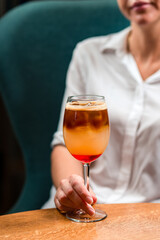 woman with a cocktail at the table, a cocktail with cold coffee and an aperol