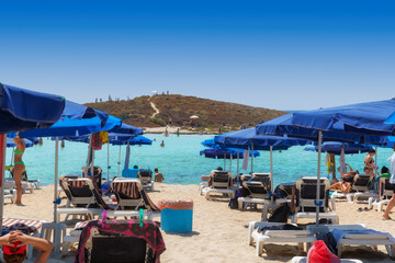 Fototapeta na wymiar Beach umbrellas and sunbeds on sandy beach in Ayia Napa, Cyprus