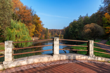 Fototapeta na wymiar Autumn landscape from river bridge. Colorful leaves in autumn park