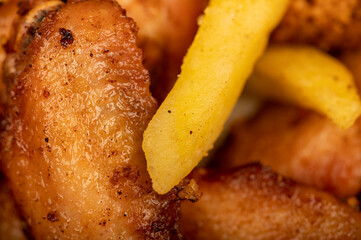 Fried chicken wings and French fries on a plate, close-up, selective focus.
