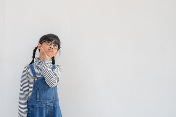 Fototapeta na wymiar Cute Asian small girl wearing glasses and thinking