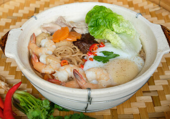 Homemade Chinese cuisine. Claypot Yee Mee Noodle Soup. Broth made from chicken carcass, dried noodle, fresh prawns, pork slices, mushrooms, deep fried tofu skin, tofu pouch, vegetables and poached egg