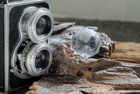 Vintage two lens photo camera with Glass crystal globe on wooden background. An idea of old camera and memory, time Nostalgia.