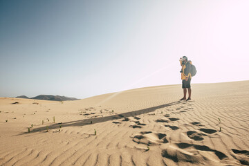 One man standing on the sand desert dunes with backpack looking far - climate change arid no water...
