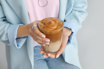 Woman drinking tasty coffee on grey background, closeup