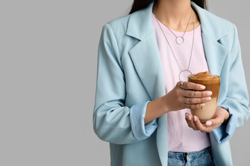Woman drinking tasty coffee on grey background, closeup