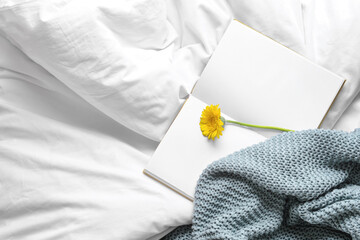 Book with flower on bed