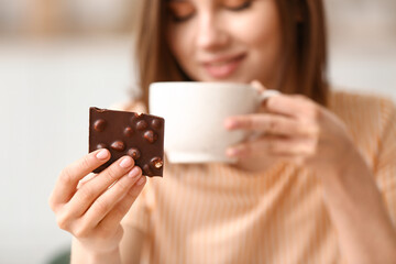 Fototapeta premium Beautiful young woman with tasty chocolate at home, closeup