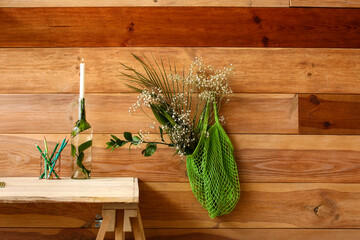 String bag with flowers hanging on wooden wall