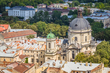 Fototapeta na wymiar View of historical old city district of Lviv in cloudy morning, Ukraine. View of Dominican Church. Early autumn. Old buildings and courtyards in historic Lviv