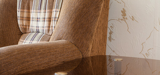 Fototapeta na wymiar large brown armchair and glass coffee table in the corner of the room