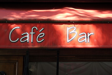 Café Bar. Lettrage blanc sur store rouge ensoleillé.