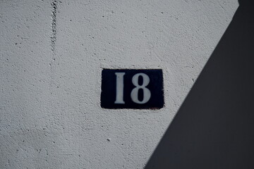 Numéro 18. Plaque de numéro de rue sur façade.