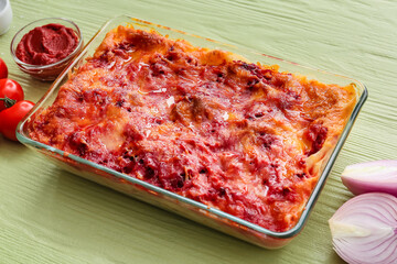 Baking dish with tasty vegetable lasagna on color wooden background