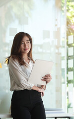 Fototapeta premium Portrait of businesswoman holding digital tablet and standing in modern office.