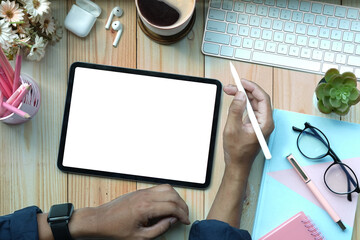 Above view creative man holding stylus pen and using digital tablet on wooden desk.